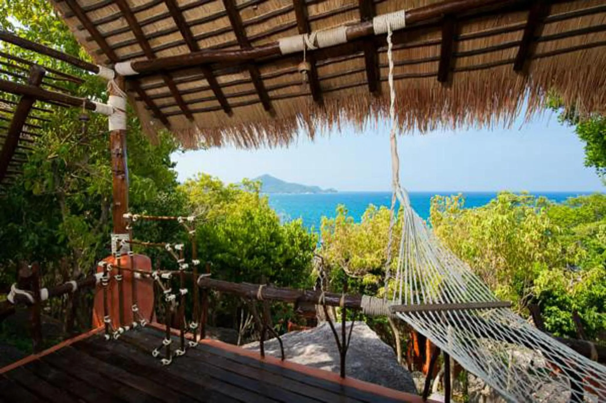 Vue sur la mer depuis une terrasse ombragée avec un hamac.