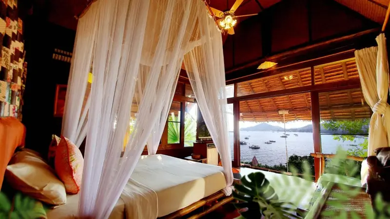 Un lit à baldaquin dans une chambre ouverte sur une vue maritime.