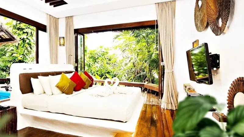 Une chambre lumineuse avec un grand lit donnant sur une végétation luxuriante.