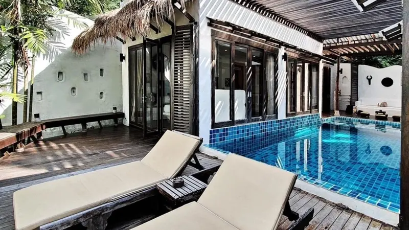 Terrasse en bois avec transats donnant sur une piscine bleue.