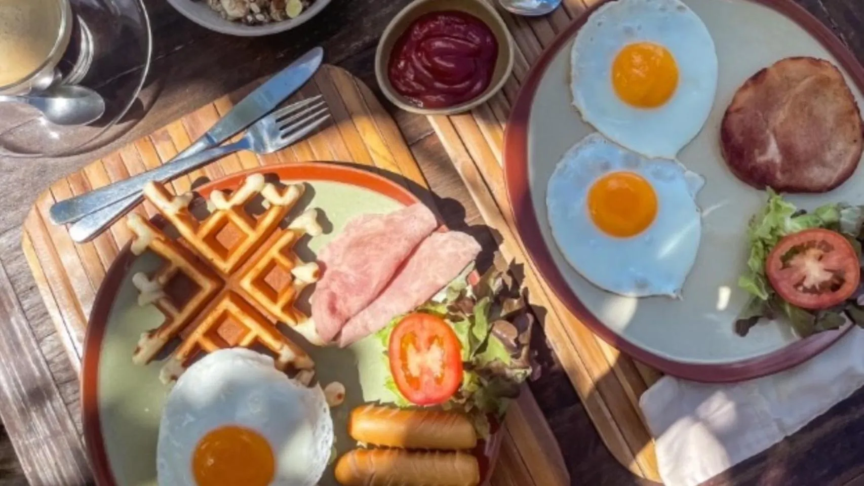 Assiette copieuse avec des œufs au plat, des gaufres et des accompagnements.