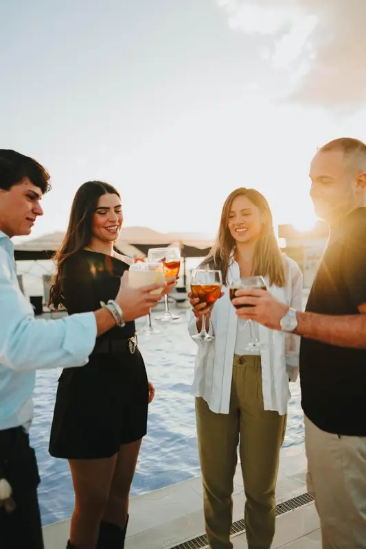 Un groupe de personnes trinque avec des verres sur une terrasse ensoleillée.