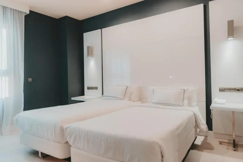 Une chambre lumineuse avec deux lits simples et un mur blanc.