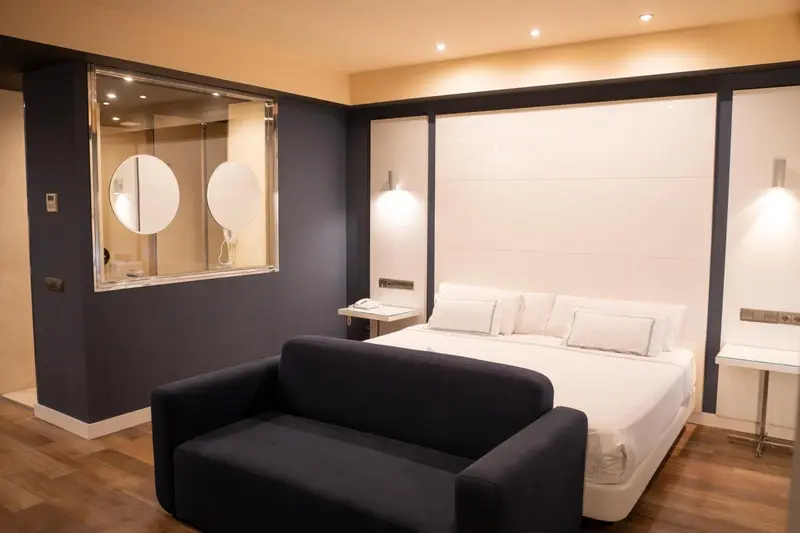 Une chambre moderne avec un lit blanc et un canapé noir.