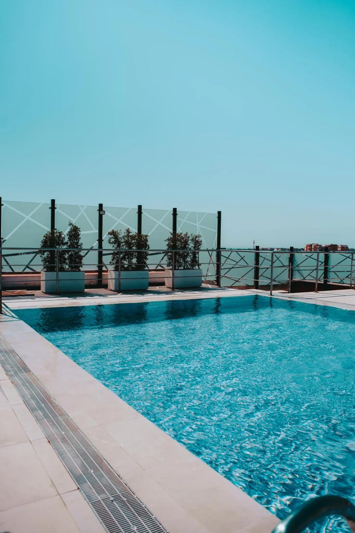 Piscine rectangulaire sur une terrasse ensoleillée avec une vue sur la mer.