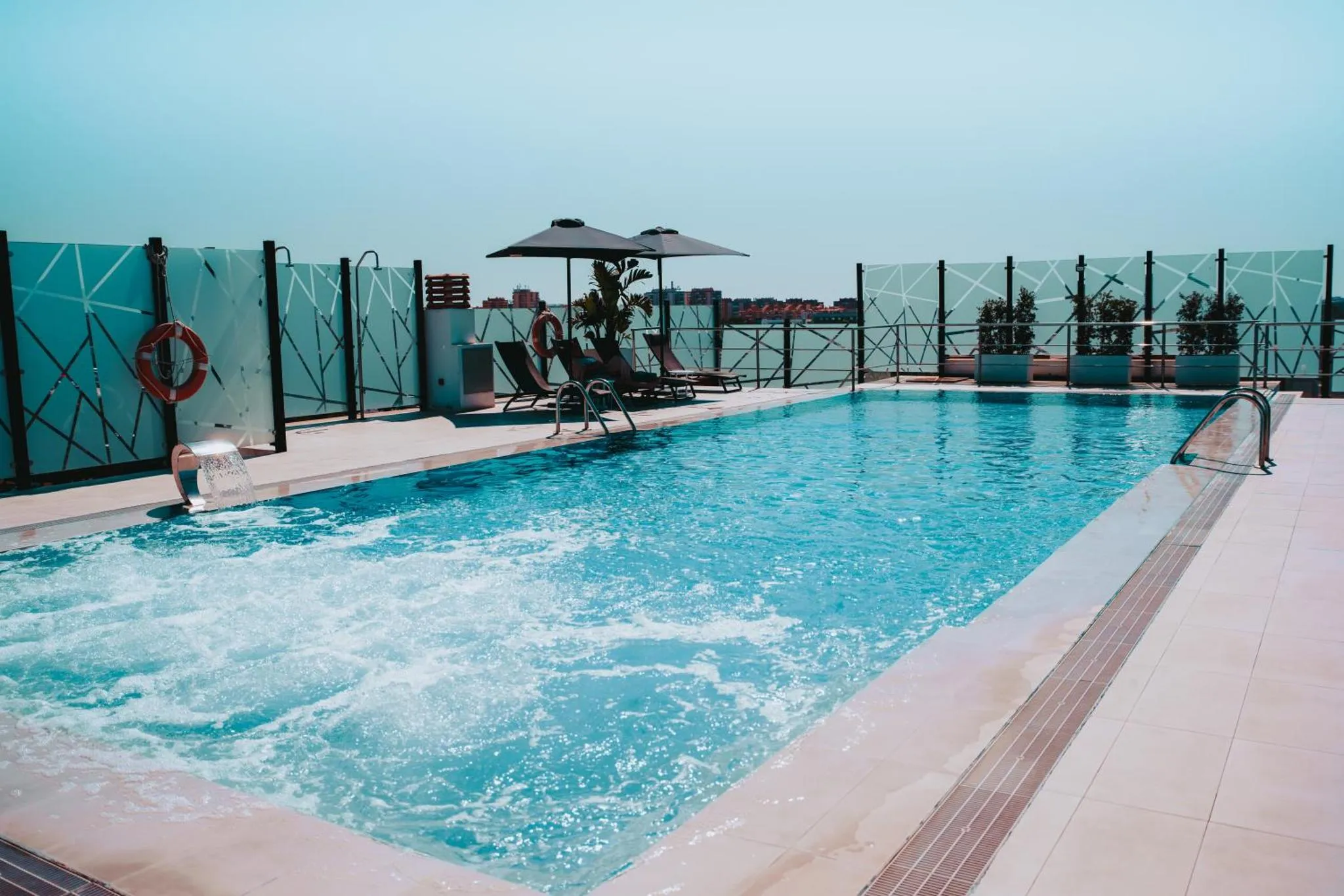 Une piscine rectangulaire avec des transats sur une terrasse ensoleillée.
