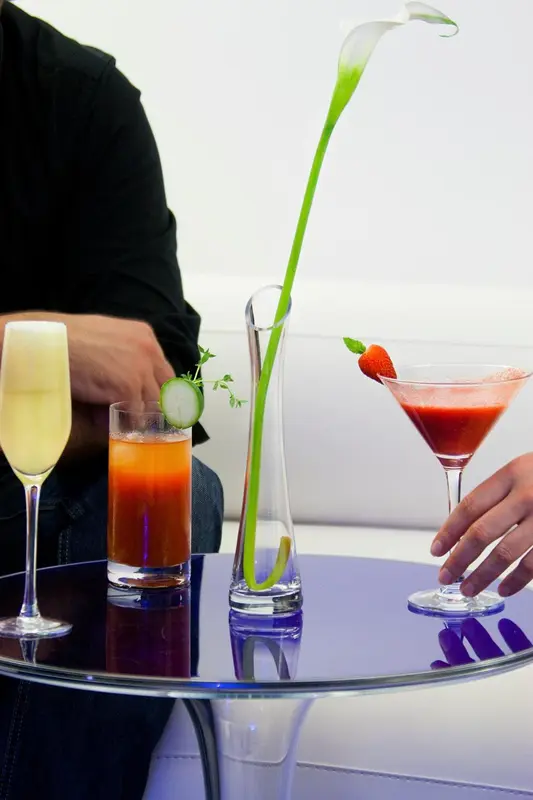 Trois verres colorés sont présentés sur une table laquée bleue.