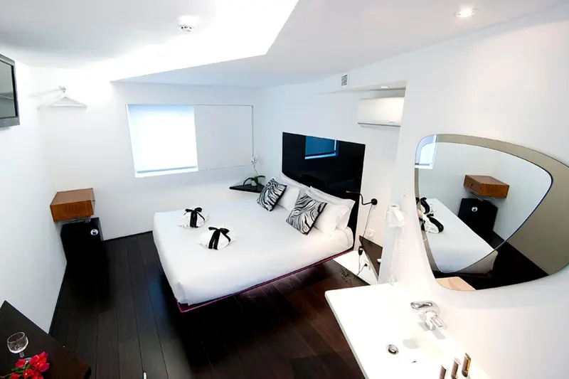 Une chambre moderne avec un grand lit et un miroir incurvé.
