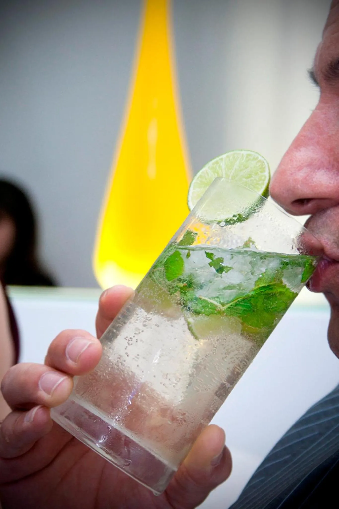 Une personne déguste une boisson fraîche avec une tranche de citron vert.