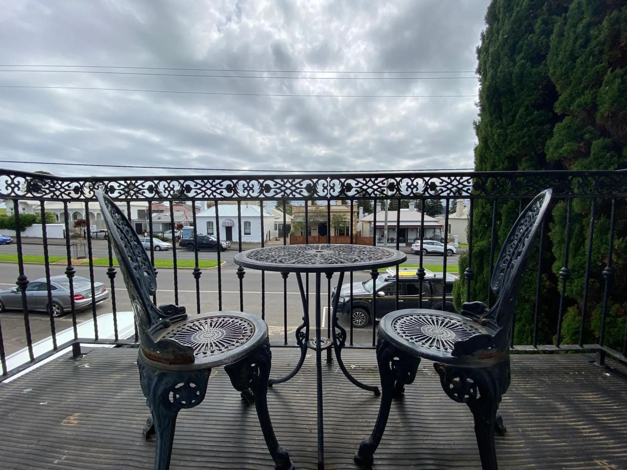 Terrasse avec mobilier en fer forgé et vue sur une rue.