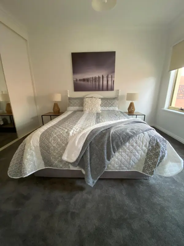Une chambre lumineuse avec un grand lit recouvert d'une courtepointe décorative.
