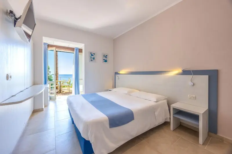 Chambre lumineuse avec un lit double et une vue sur la mer.