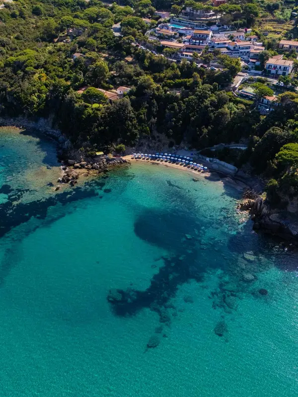 Vue aérienne d'une crique abritée avec une plage de sable et des parasols.