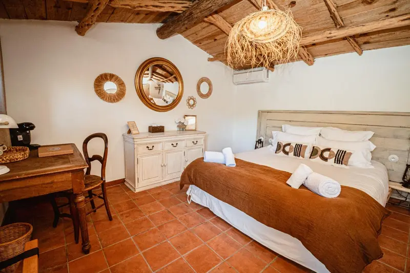 Une chambre lumineuse avec un lit double et un bureau en bois.