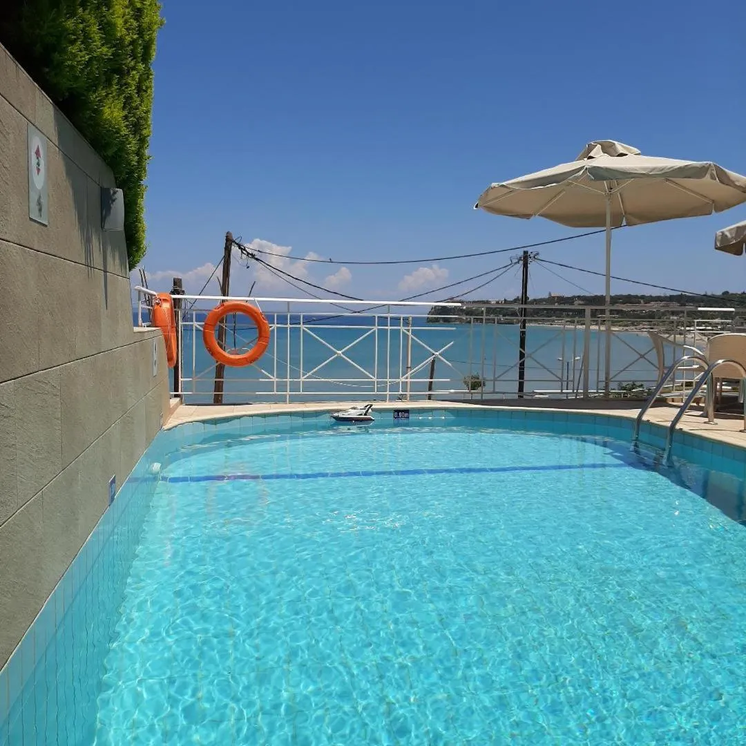 Petite piscine rectangulaire avec un parasol et une vue sur la mer.