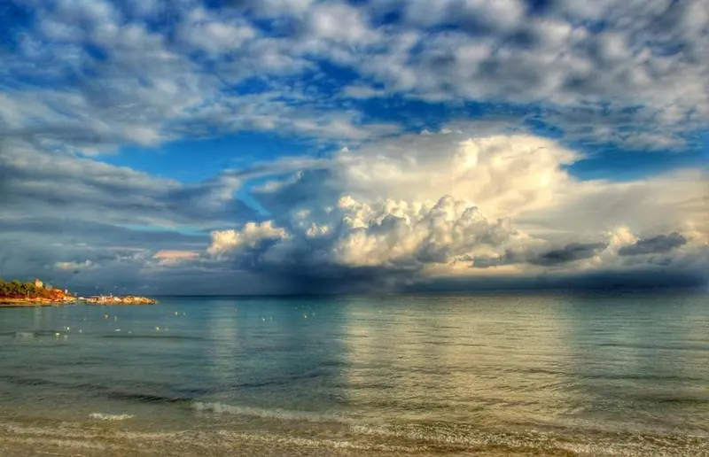 Ciel nuageux au-dessus d'une plage ensoleillée.