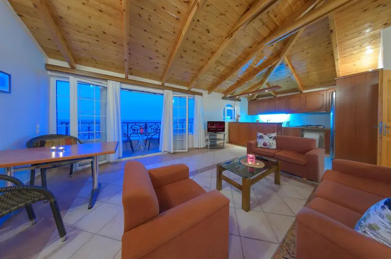 Espace de vie lumineux avec canapés, table basse et vue sur la mer par de grandes baies vitrées.
