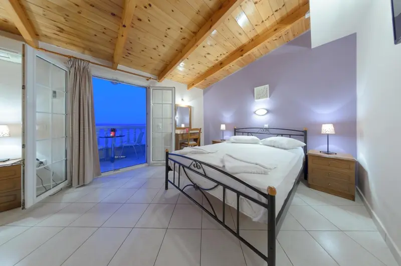 Chambre lumineuse avec lit double et vue sur la mer.