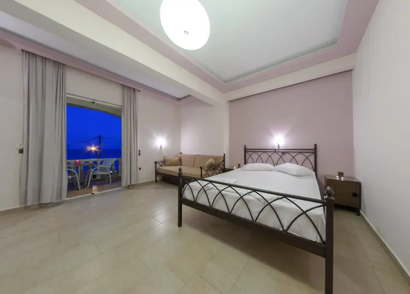 Une chambre lumineuse avec un lit et un canapé face à une baie vitrée.