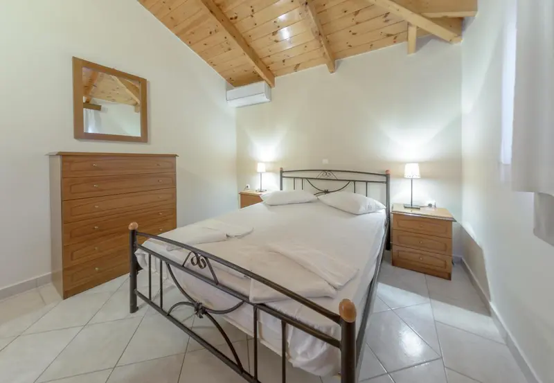 Une chambre lumineuse avec un lit double et une commode en bois.