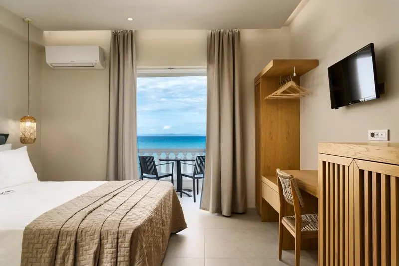 Une chambre lumineuse avec un lit et un bureau donnant sur la mer.