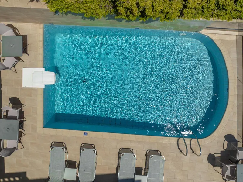 Vue aérienne d'une piscine rectangulaire entourée de transats.