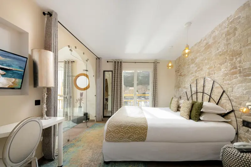 Chambre lumineuse avec un grand lit et un mur en pierre.
