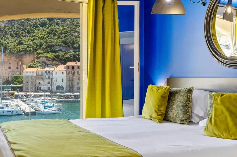 Une chambre lumineuse avec vue sur un port de plaisance.