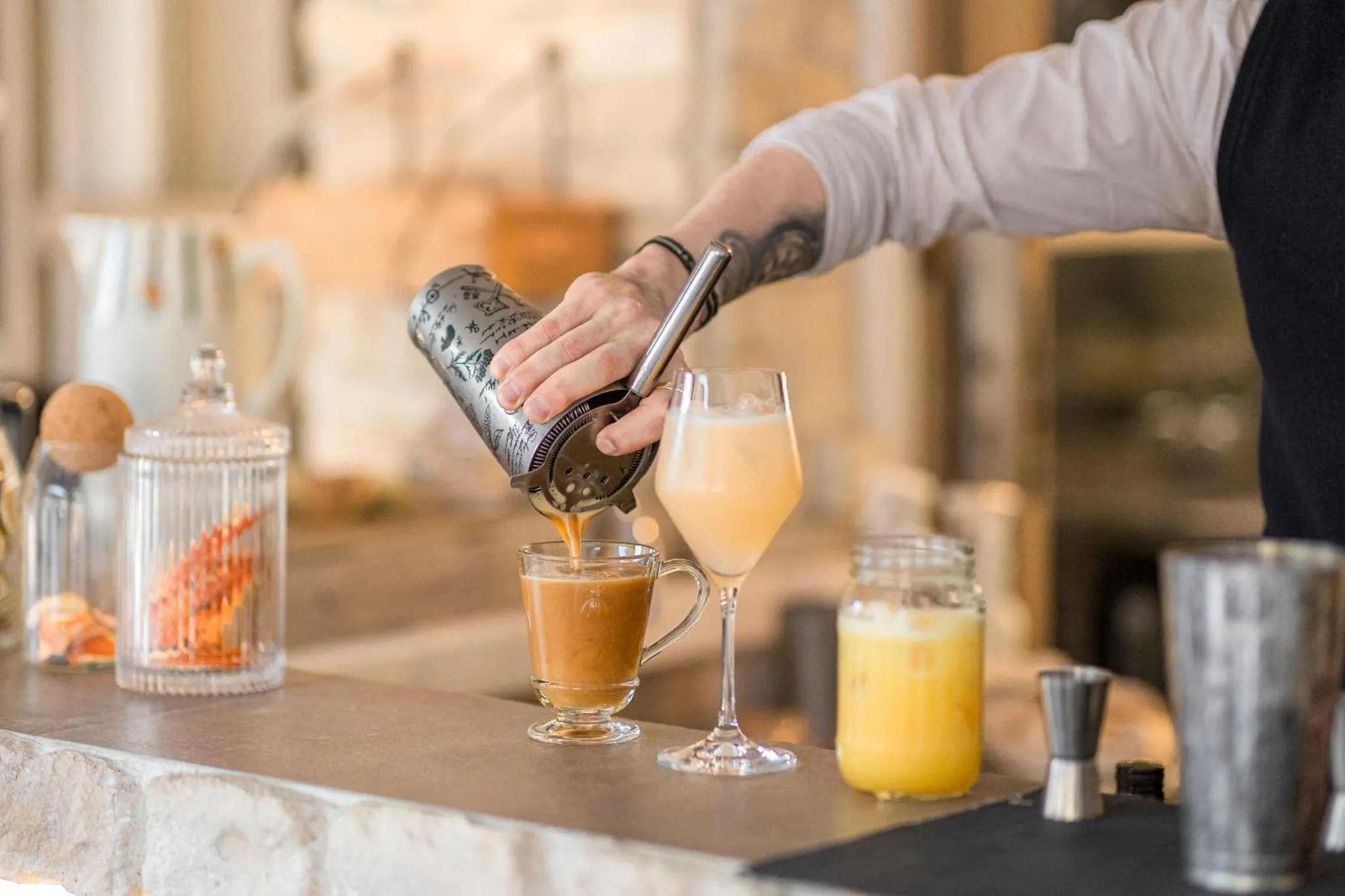 Un barman prépare un cocktail derrière un comptoir.