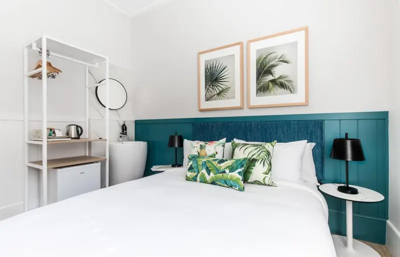 Une chambre lumineuse avec un lit recouvert d'oreillers décoratifs et un bureau.