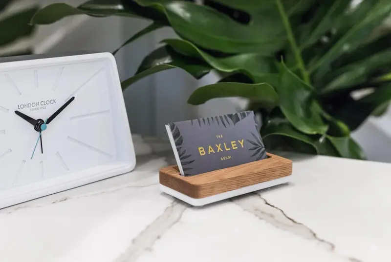 Une horloge et un présentoir à cartes de visite sur une surface marbrée.