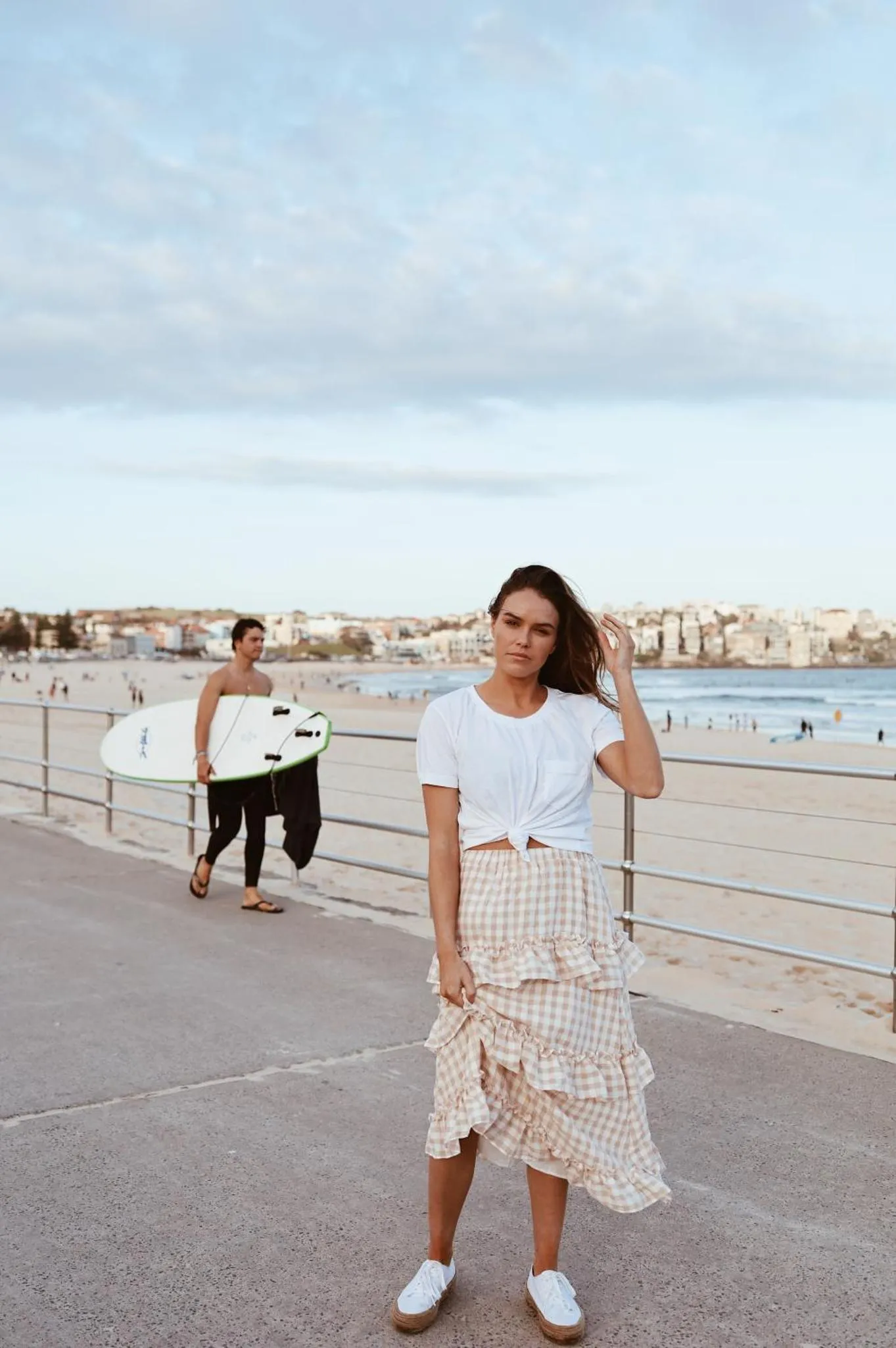Une jeune femme regarde l'objectif sur une promenade en bord de mer.