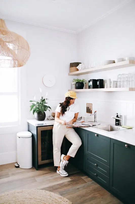 Une personne est adossee a un plan de travail dans une cuisine lumineuse.