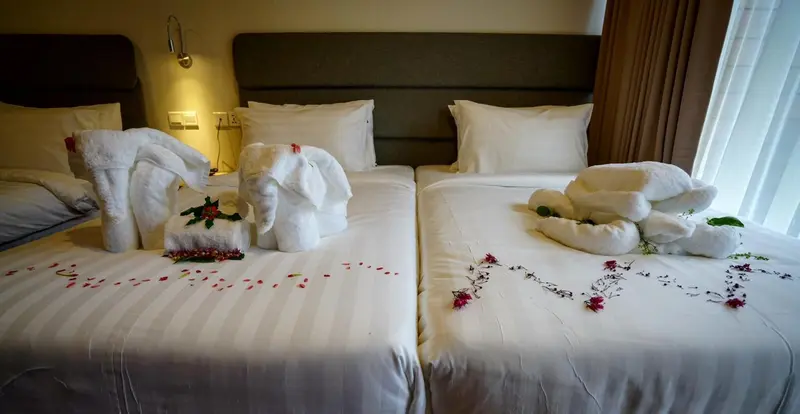 Lits préparés avec des décorations en serviettes en forme d'animaux et de fleurs.