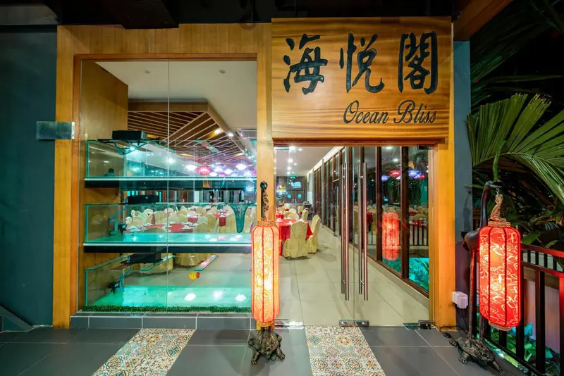 Entrée illuminée d'un restaurant avec des tables dressées et une décoration asiatique.