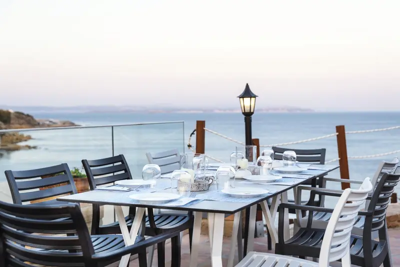 Une table dressée sur une terrasse avec vue sur la mer.