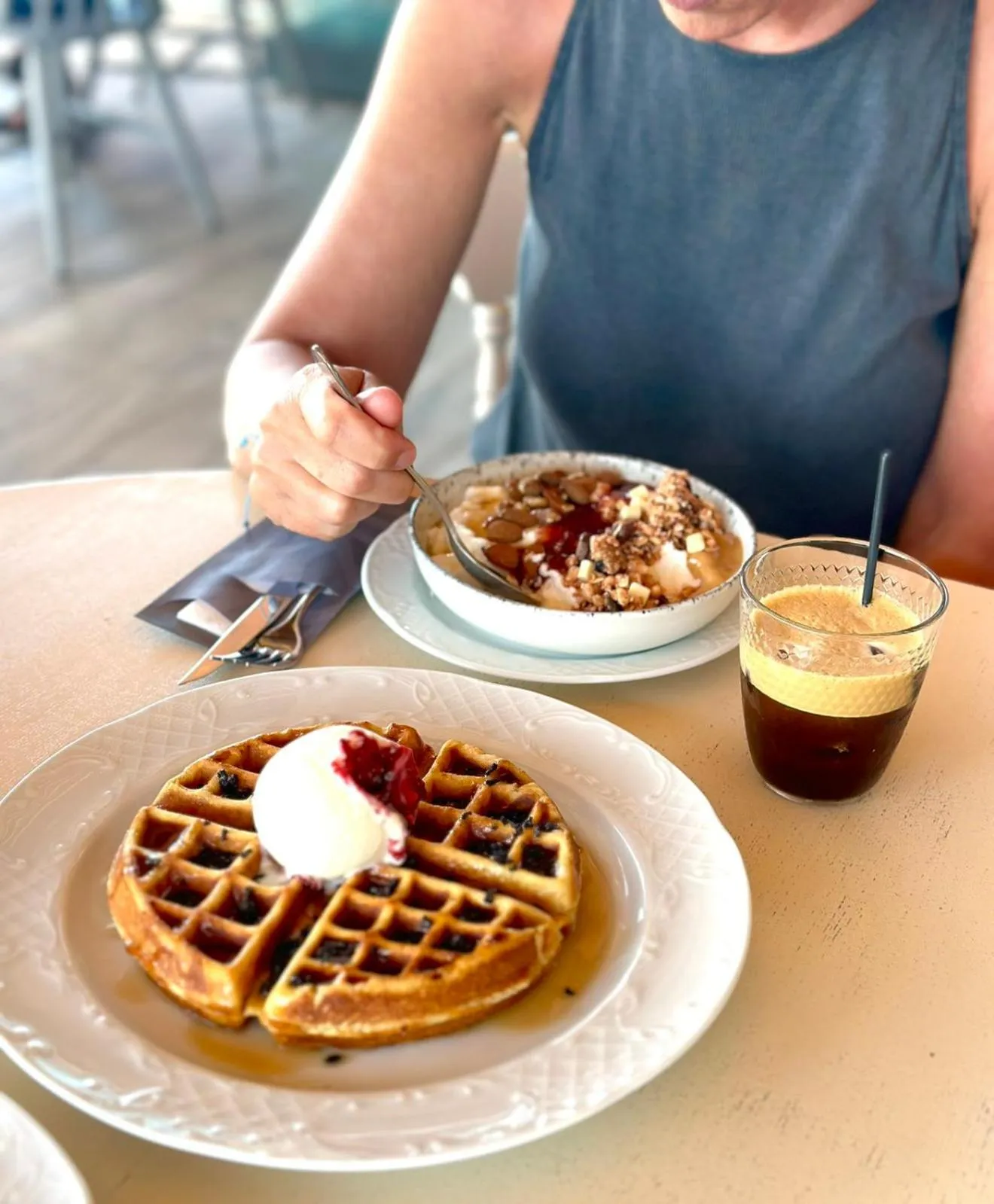 Une personne déguste un dessert et une boisson à table.
