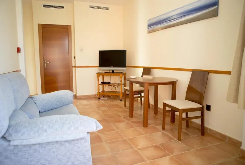 Espace de vie lumineux avec canapé, table et télévision.