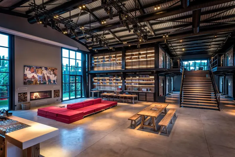 Vaste espace intérieur avec canapés, tables et escalier menant à une mezzanine.