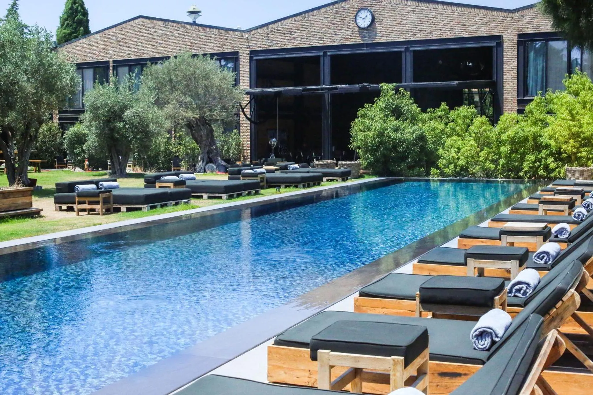 Une piscine rectangulaire bordée de transats et de parasols.