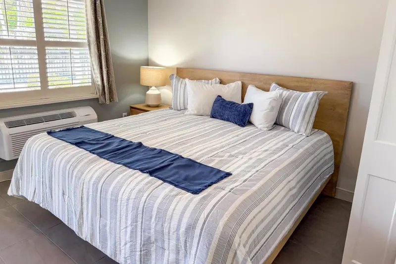 Une chambre lumineuse avec un grand lit recouvert d'une courtepointe rayée.