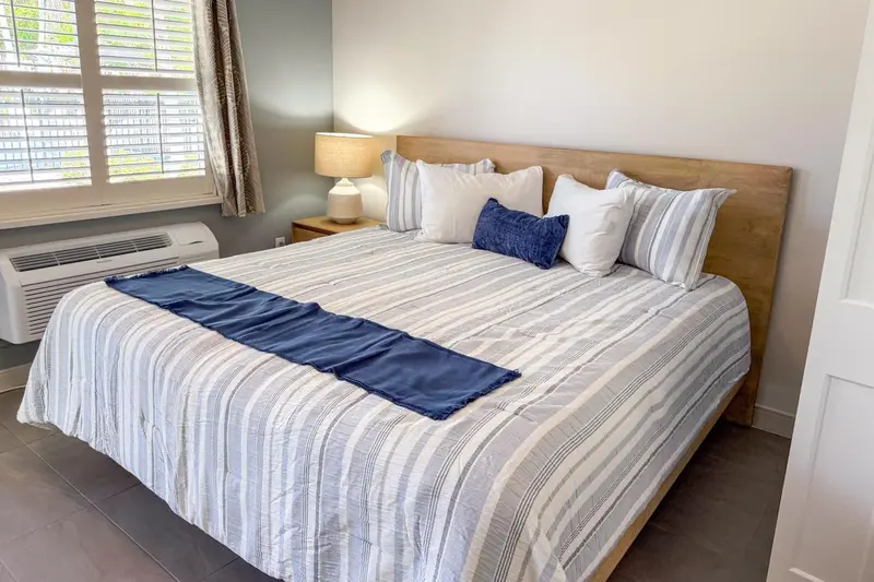 Une chambre lumineuse avec un grand lit recouvert d'une courtepointe rayée.