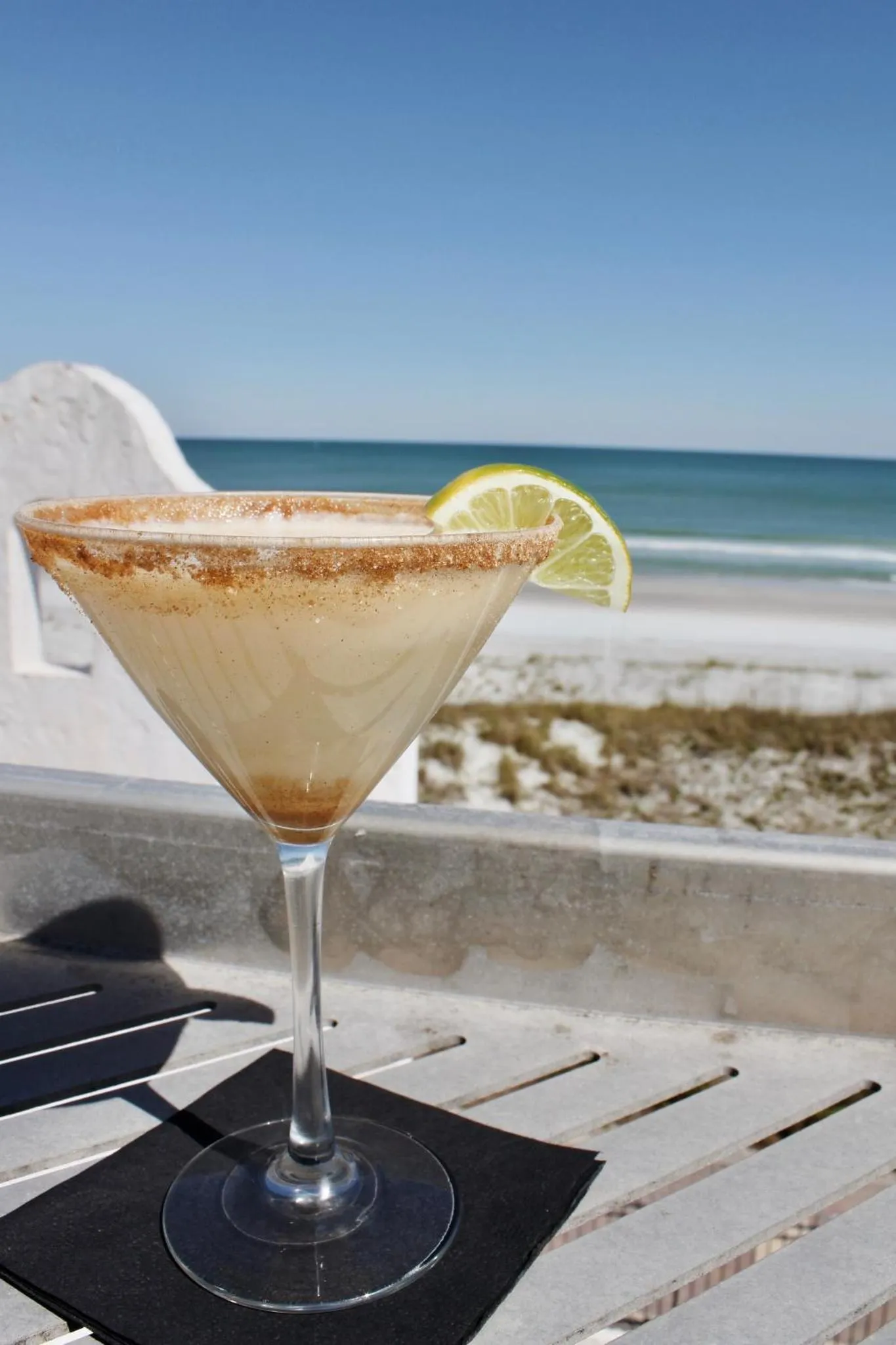 Un cocktail coloré est servi sur une table en bord de mer.