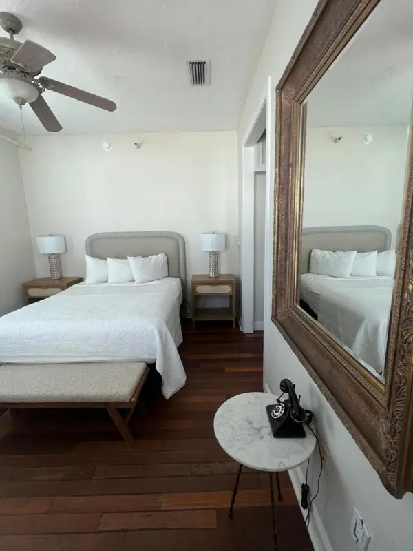 Une chambre lumineuse avec un grand lit et un miroir décoratif.
