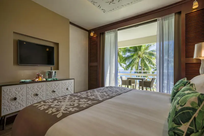 Une chambre lumineuse avec un lit et une vue sur la végétation tropicale.