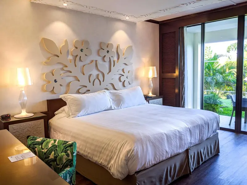 Une chambre lumineuse avec un grand lit et une décoration florale sur le mur.