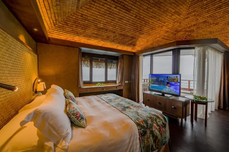 Une chambre lumineuse avec un lit recouvert d'une courtepointe colorée et une vue sur l'océan.