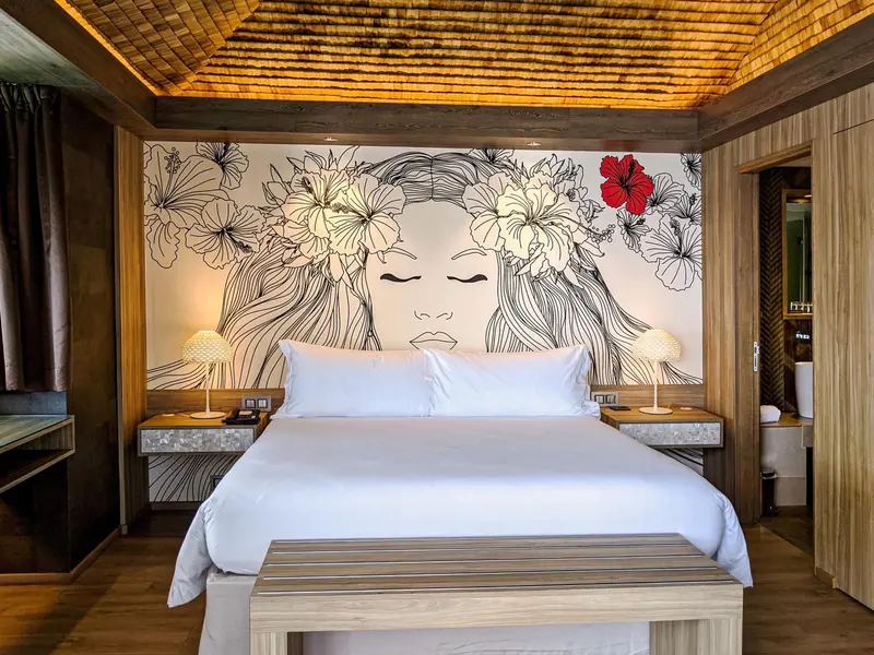 Une chambre lumineuse avec un grand lit et un mur décoré d'un motif floral.