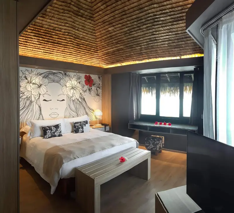 Une chambre lumineuse avec un lit blanc et une décoration florale sur le mur.