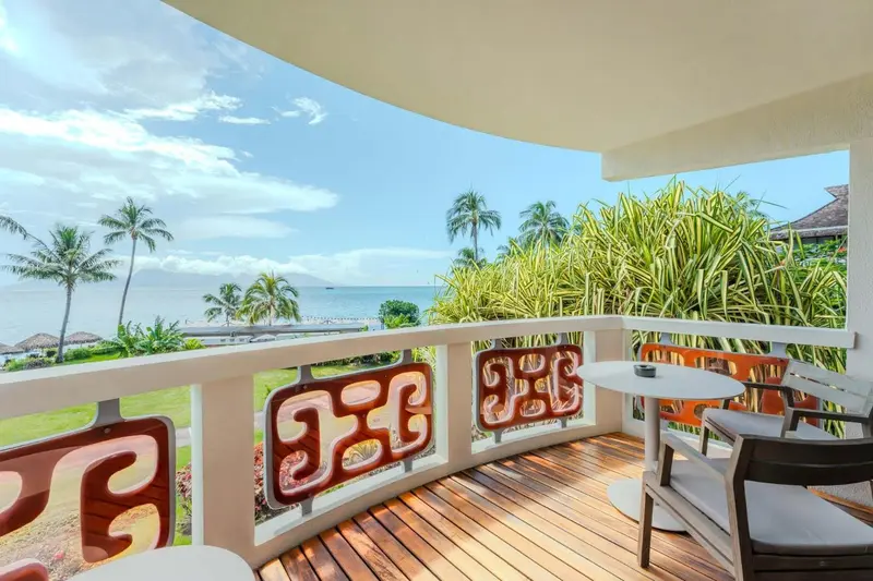 Une terrasse ensoleillée offre une vue sur la mer et la végétation tropicale.